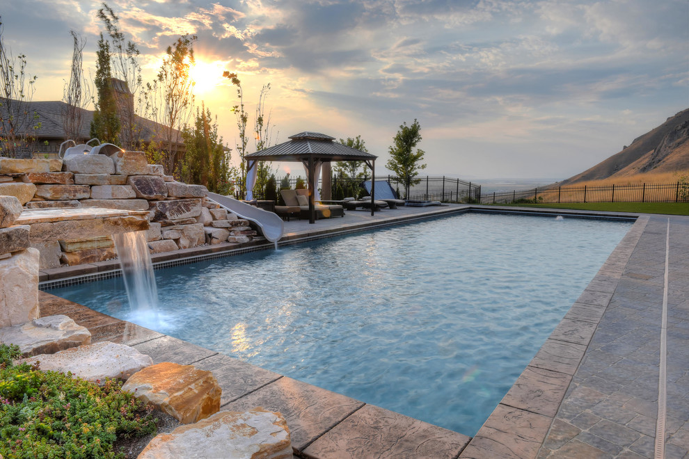 Photo of a rustic back rectangular lengths swimming pool in Salt Lake City with a water slide.