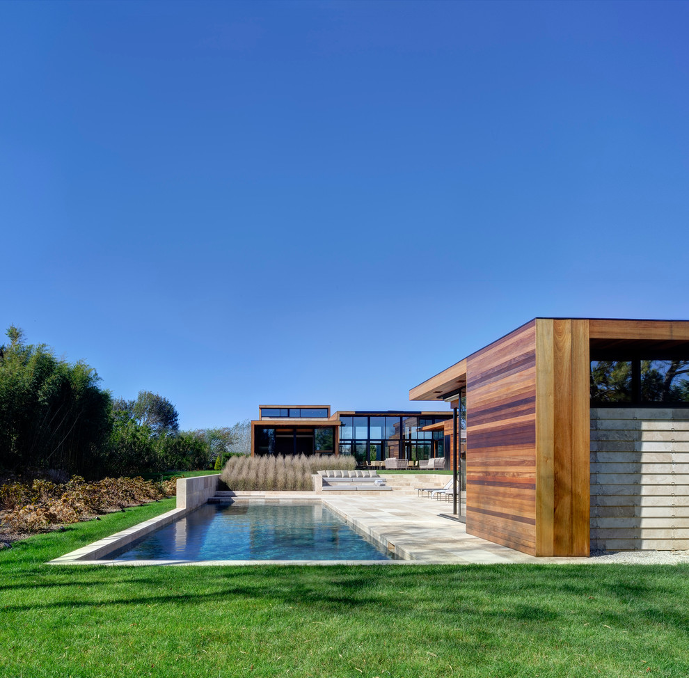 Diseño de casa de la piscina y piscina contemporánea grande rectangular en patio trasero con adoquines de piedra natural