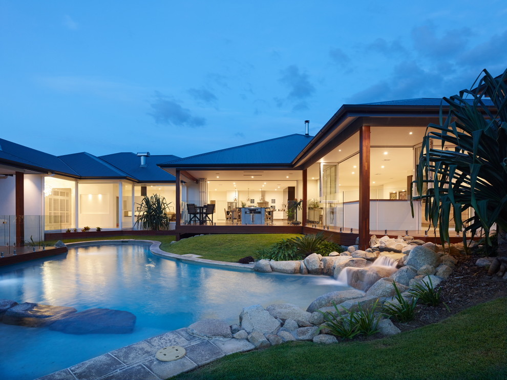 Large island style backyard stone and custom-shaped infinity pool photo in Brisbane