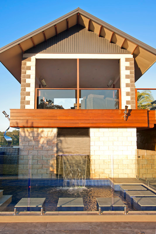 Bild på en stor funkis l-formad ovanmarkspool på baksidan av huset, med poolhus och kakelplattor