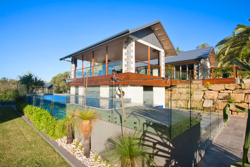 Immagine di una grande piscina fuori terra design a "L" dietro casa con una dépendance a bordo piscina e piastrelle