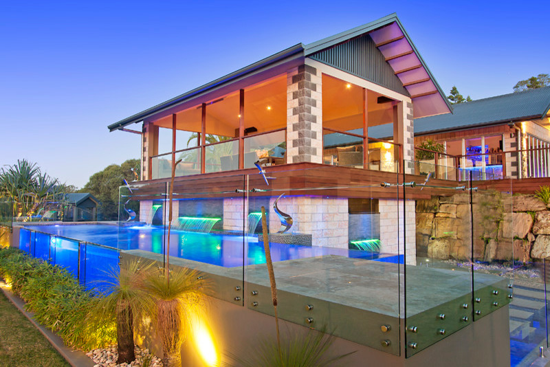 На фото: большой наземный, угловой бассейн на заднем дворе в современном стиле с домиком у бассейна и покрытием из плитки