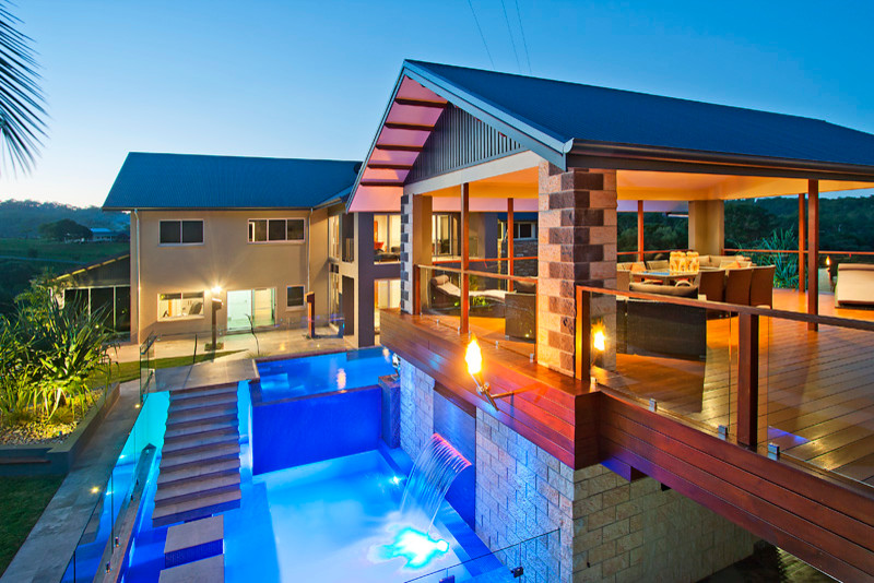 Foto di una grande piscina fuori terra design a "L" dietro casa con una dépendance a bordo piscina e piastrelle