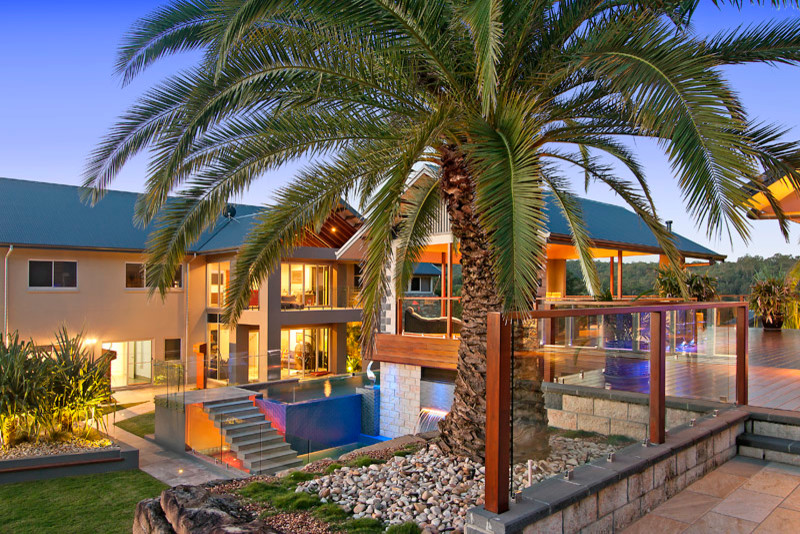 Foto de casa de la piscina y piscina elevada actual grande en forma de L en patio trasero con suelo de baldosas