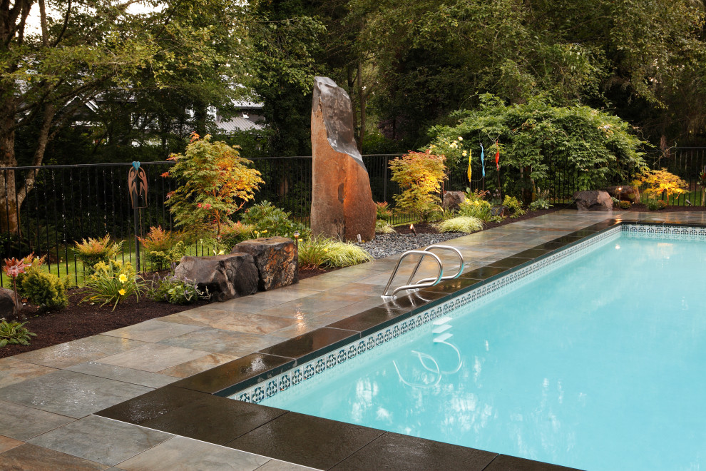 Foto di una grande piscina monocorsia design rettangolare dietro casa con fontane e pavimentazioni in pietra naturale
