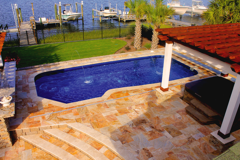 Diseño de piscina con fuente natural tradicional grande en forma de L en patio trasero con suelo de baldosas