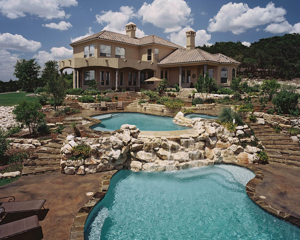 Esempio di un'ampia piscina naturale stile rurale personalizzata dietro casa con una dépendance a bordo piscina e pavimentazioni in cemento