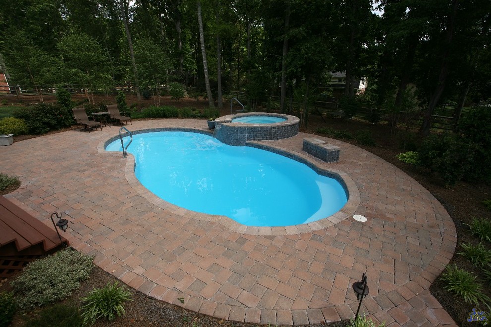 Diseño de piscina clásica de tamaño medio a medida en patio trasero con adoquines de ladrillo