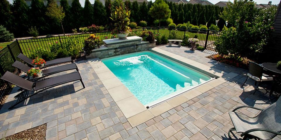 Imagen de piscina con fuente alargada minimalista de tamaño medio rectangular en patio trasero con adoquines de hormigón