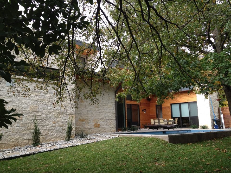 Ispirazione per una grande piscina naturale minimalista rettangolare dietro casa con pavimentazioni in pietra naturale
