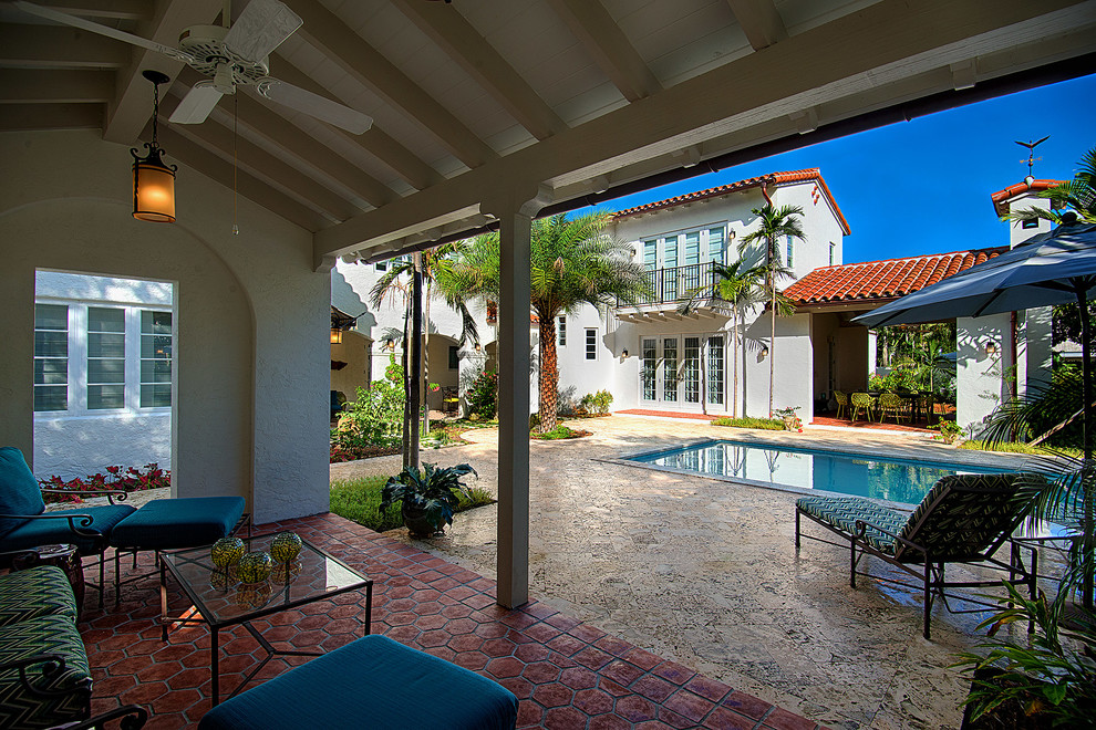Example of a large tuscan courtyard stone and rectangular pool design in Miami