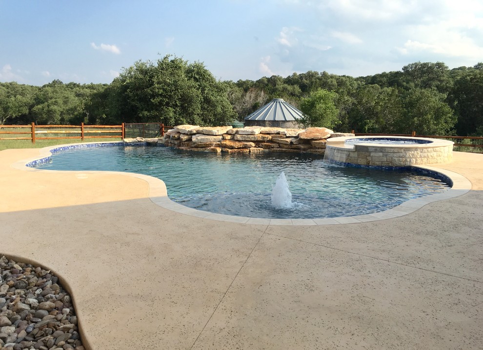 Стильный дизайн: большой естественный бассейн в форме фасоли на заднем дворе в классическом стиле с фонтаном и покрытием из бетонных плит - последний тренд