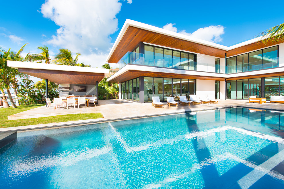 Diseño de piscinas y jacuzzis infinitos minimalistas grandes rectangulares en patio trasero con adoquines de piedra natural