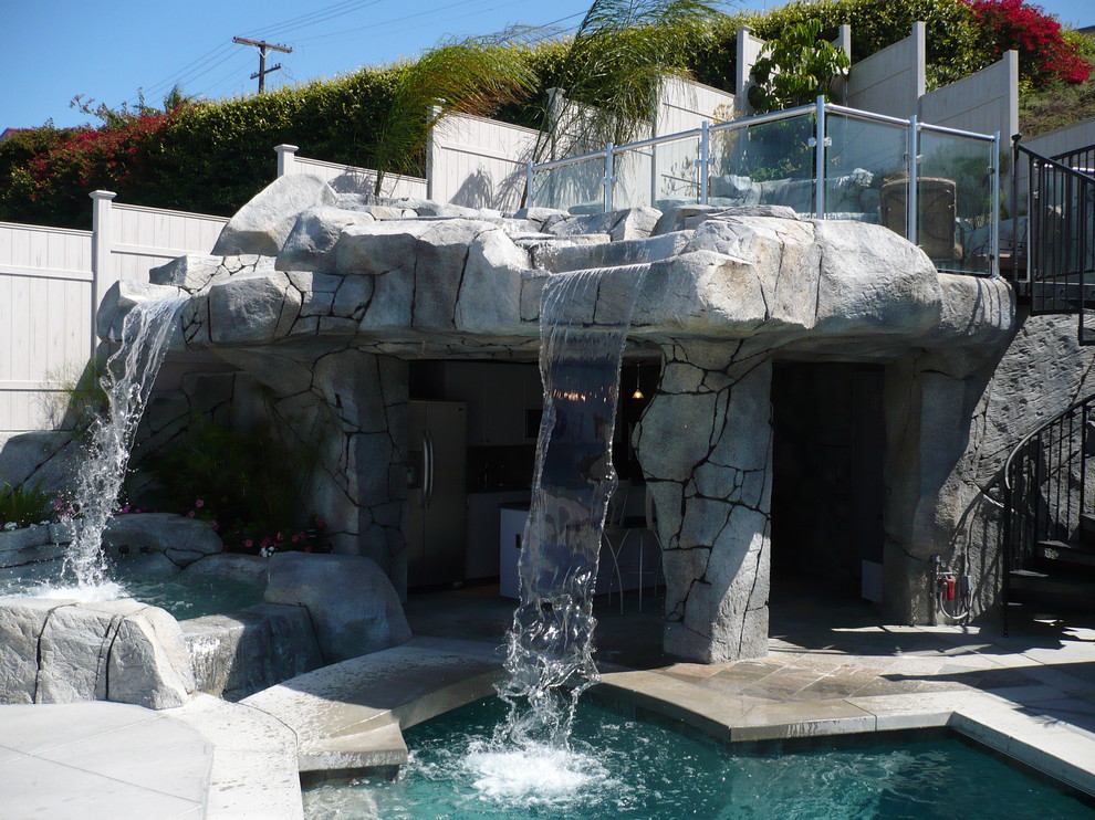 This is an example of a bohemian custom shaped natural swimming pool in Orange County with a water feature.