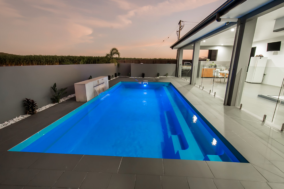 Idee per una piscina minimalista rettangolare di medie dimensioni e dietro casa con fontane e piastrelle