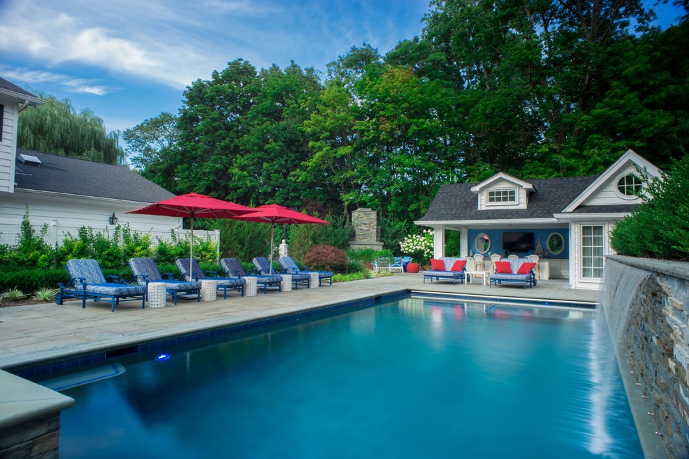 Medium sized classic back rectangular swimming pool in New York with a pool house and natural stone paving.