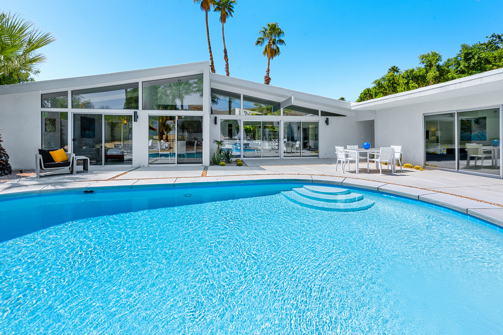 Imagen de casa de la piscina y piscina natural retro grande tipo riñón en patio trasero con losas de hormigón