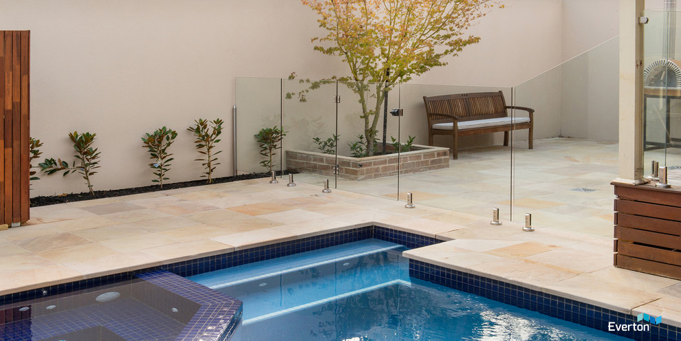 Contemporary back custom shaped swimming pool in Melbourne with natural stone paving.