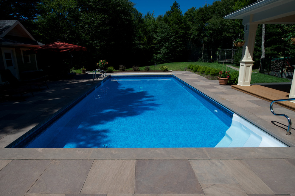 Exempel på en mellanstor modern rektangulär pool på baksidan av huset, med naturstensplattor och spabad