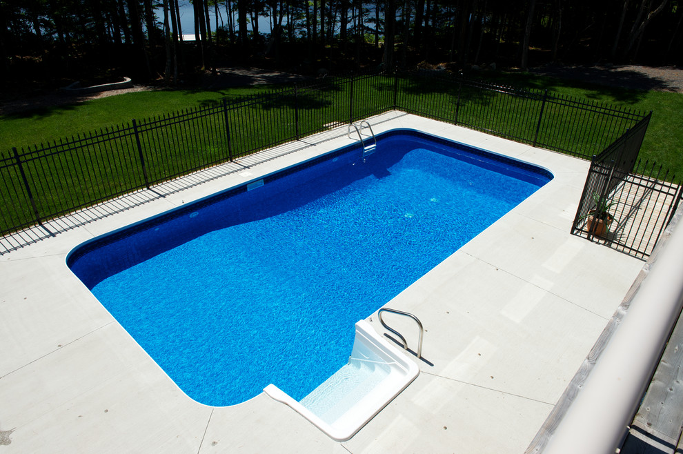 Ejemplo de piscina clásica de tamaño medio rectangular en patio trasero con losas de hormigón
