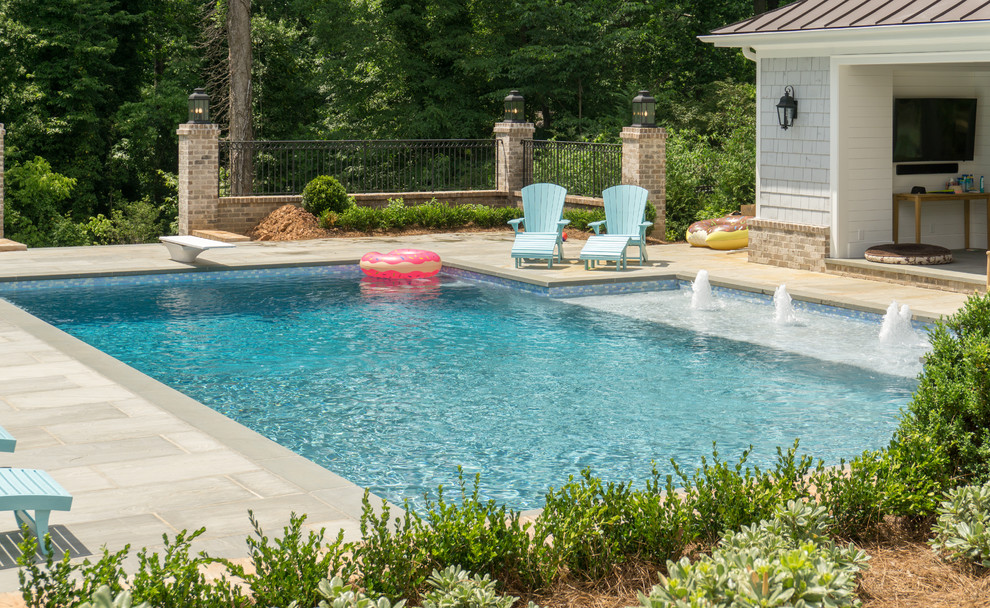 Diseño de piscina con fuente de estilo americano grande rectangular en patio trasero con adoquines de hormigón