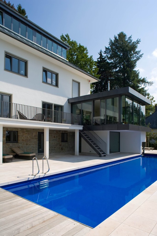 Aménagement d'un grand couloir de nage arrière contemporain rectangle avec une terrasse en bois.