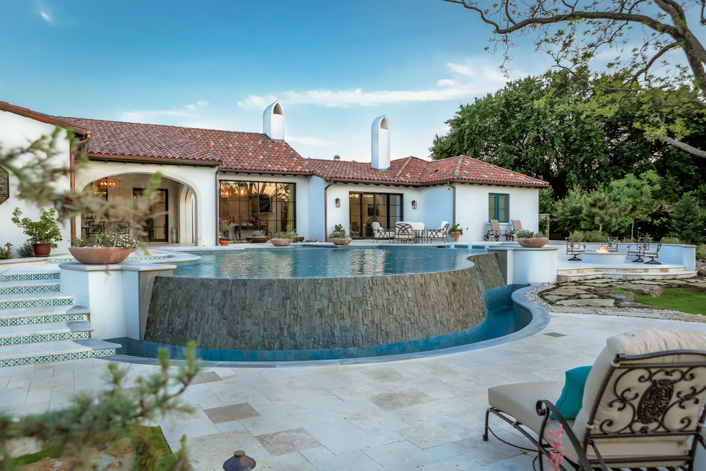 Foto di un'ampia piscina a sfioro infinito american style personalizzata dietro casa con pavimentazioni in pietra naturale