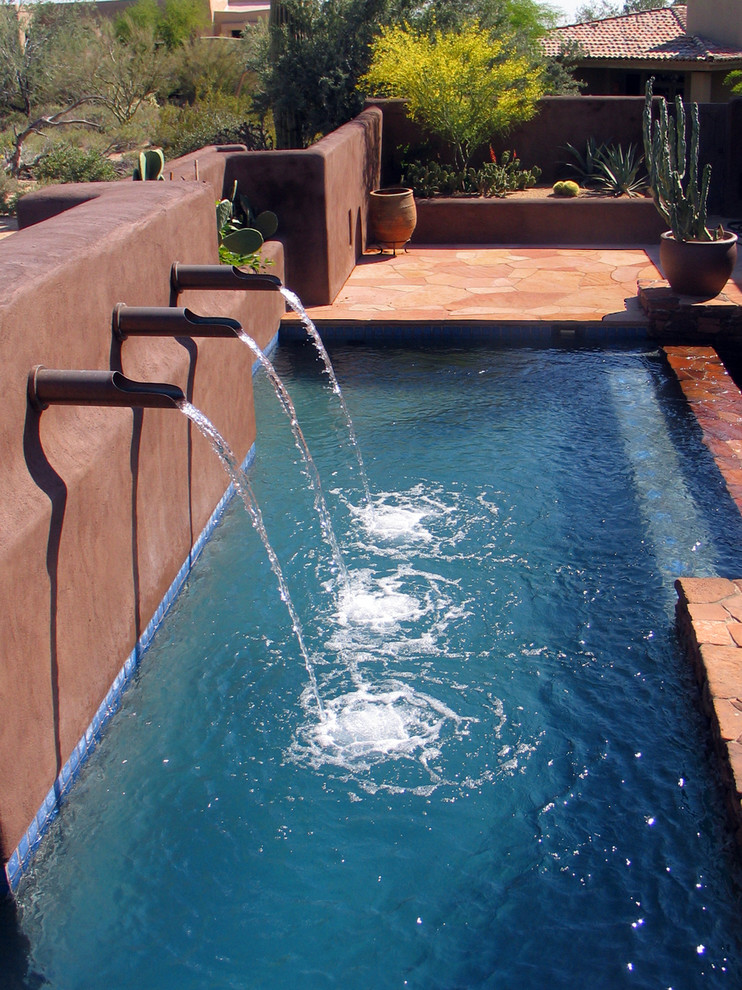 Modelo de piscinas y jacuzzis infinitos de estilo americano de tamaño medio rectangulares en patio trasero con adoquines de piedra natural