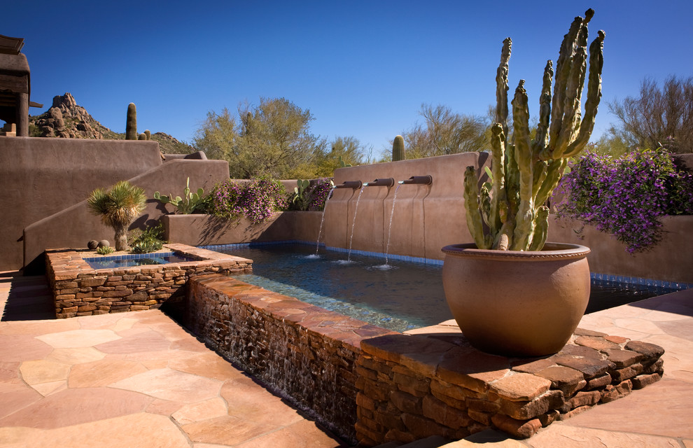 Réalisation d'une piscine à débordement et arrière sud-ouest américain de taille moyenne et rectangle avec un bain bouillonnant et des pavés en pierre naturelle.