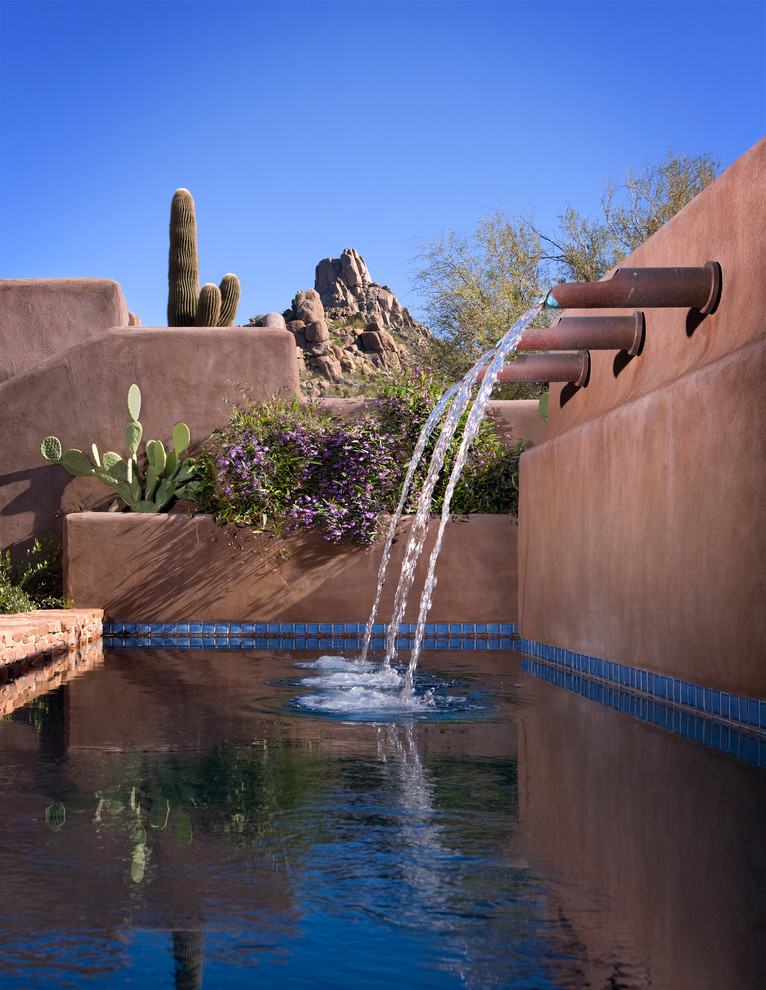 Aménagement d'une piscine à débordement et arrière sud-ouest américain de taille moyenne et rectangle avec un bain bouillonnant et des pavés en pierre naturelle.