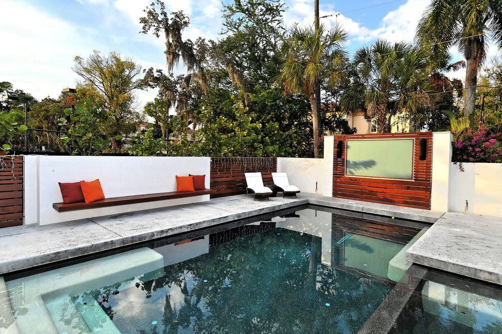 Modelo de casa de la piscina y piscina alargada contemporánea grande rectangular en patio trasero con losas de hormigón