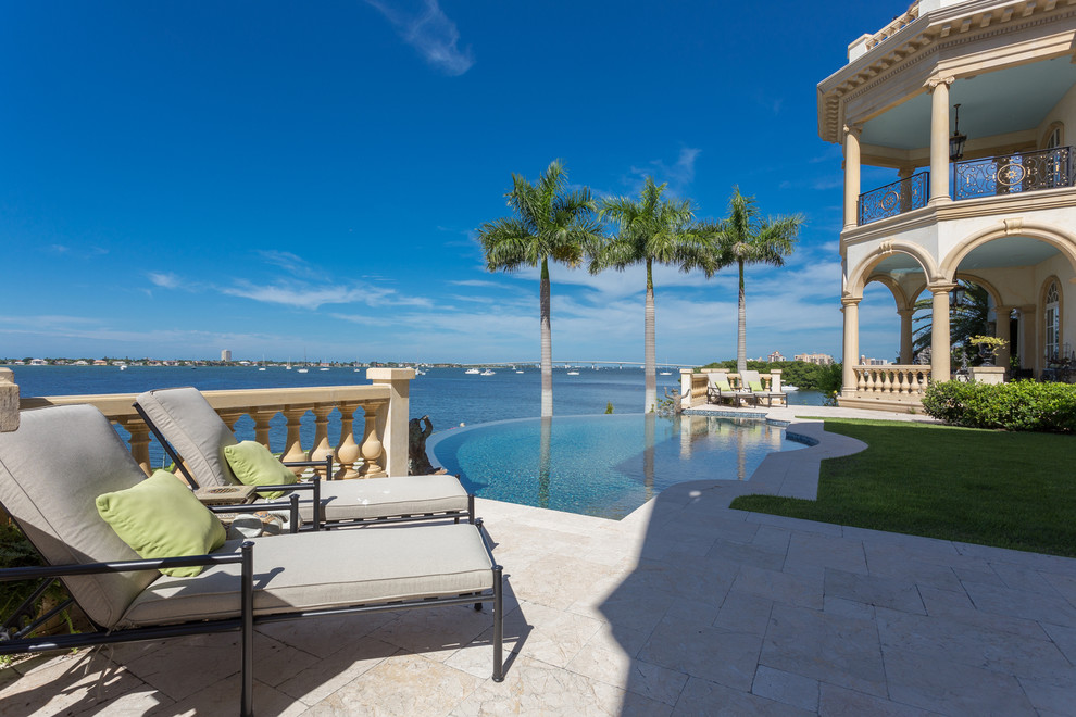 Example of a tuscan backyard tile infinity pool design in Tampa