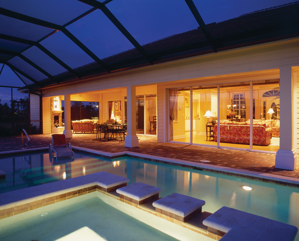 Imagen de piscina con fuente campestre de tamaño medio en patio trasero con adoquines de hormigón