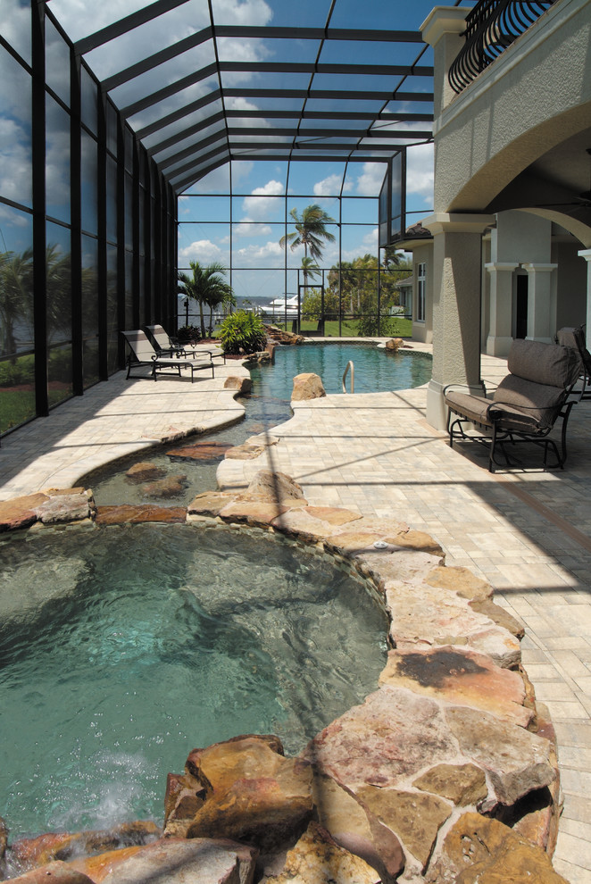 Imagen de piscina con fuente mediterránea extra grande a medida en patio trasero con adoquines de hormigón