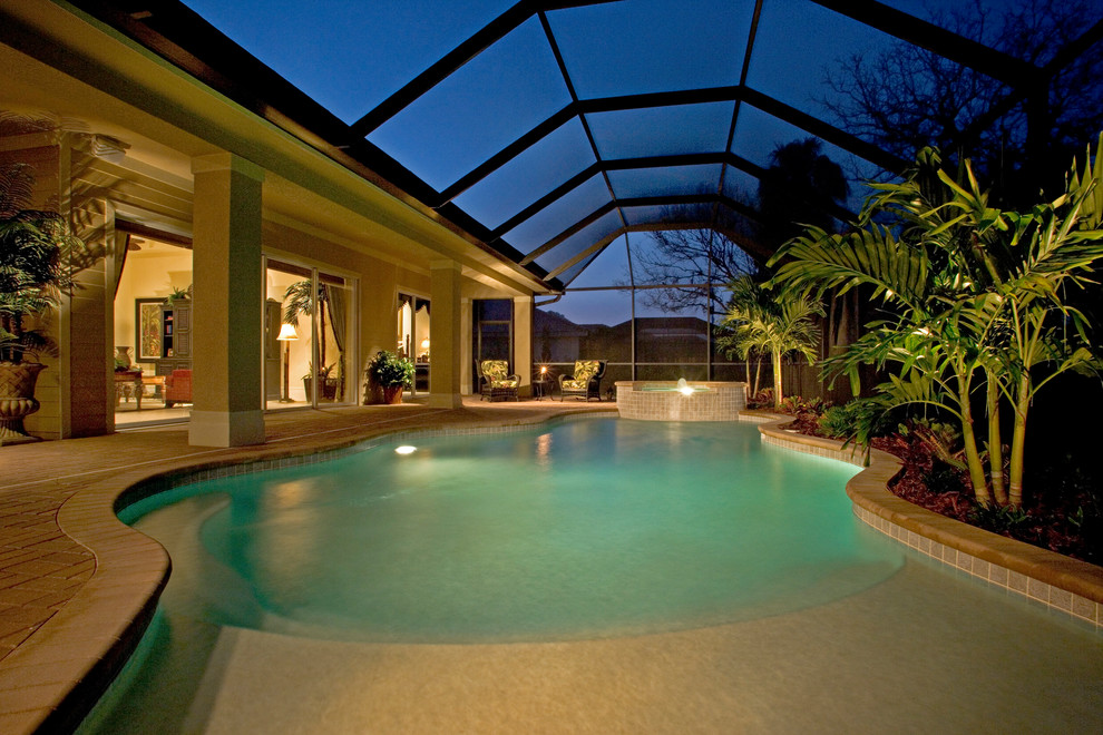 Ejemplo de piscina con fuente de estilo de casa de campo grande en patio trasero con adoquines de ladrillo