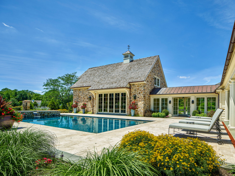 Foto di una piscina chic rettangolare dietro casa con pavimentazioni in pietra naturale