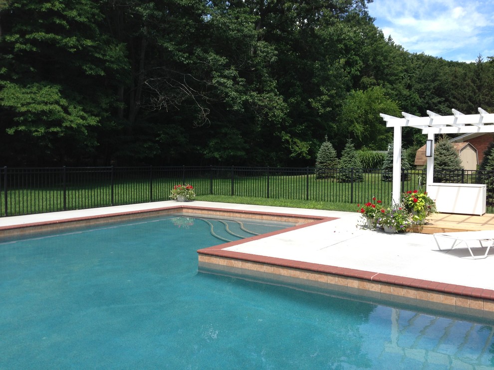 Foto di una grande piscina minimal a "L" dietro casa con una dépendance a bordo piscina e pavimentazioni in pietra naturale