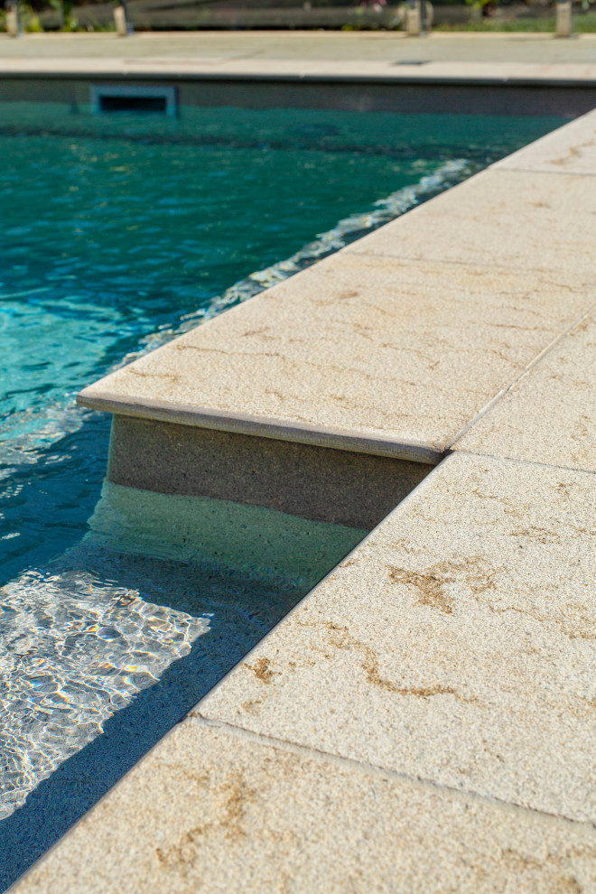Réalisation d'une piscine arrière marine de taille moyenne et rectangle avec des pavés en pierre naturelle.
