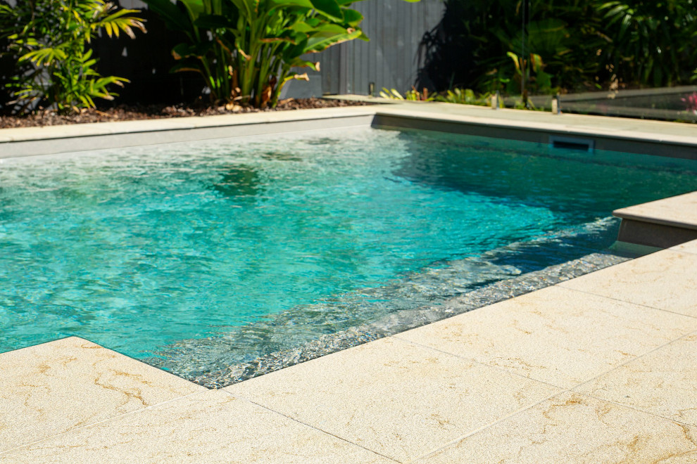 Ejemplo de piscina alargada costera de tamaño medio rectangular en patio trasero con paisajismo de piscina y adoquines de piedra natural