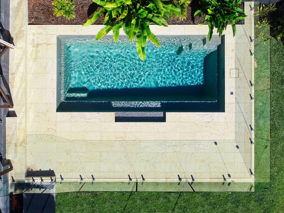Modelo de piscina alargada costera de tamaño medio rectangular en patio trasero con paisajismo de piscina y adoquines de piedra natural