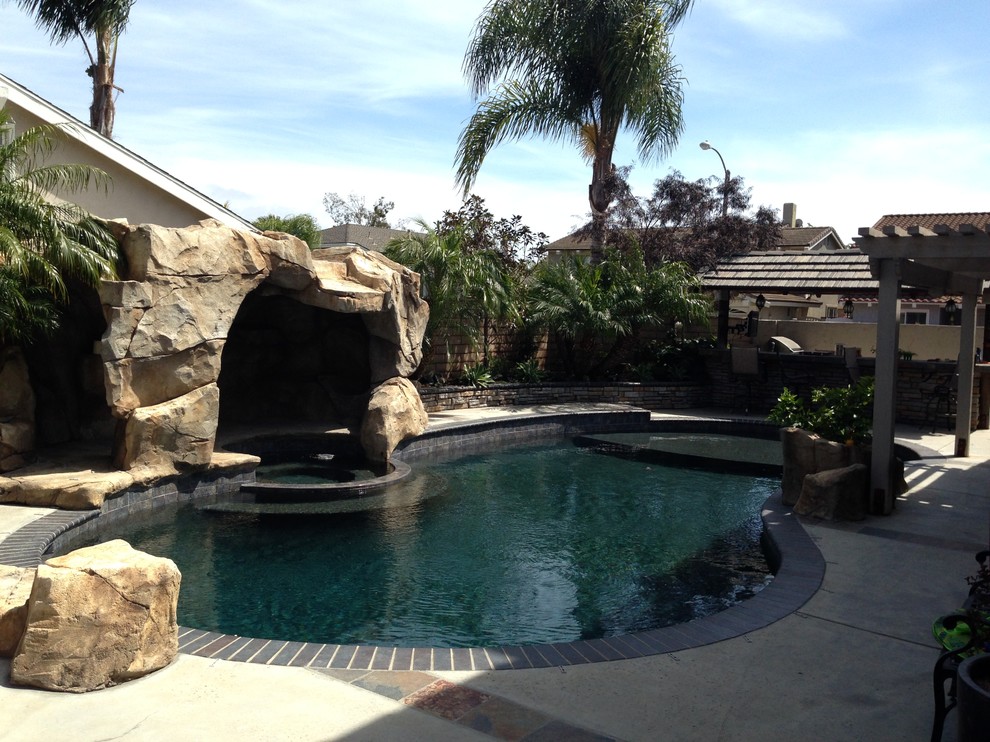 Großer Mediterraner Schwimmteich hinter dem Haus in Nierenform mit Wasserspiel und Dielen in Orange County