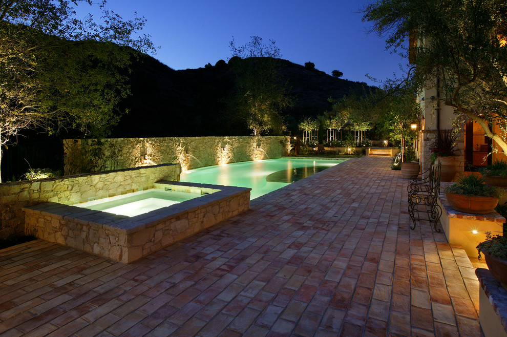 Mittelgroßer, Gefliester Mediterraner Pool hinter dem Haus in individueller Form mit Wasserspiel in Orange County