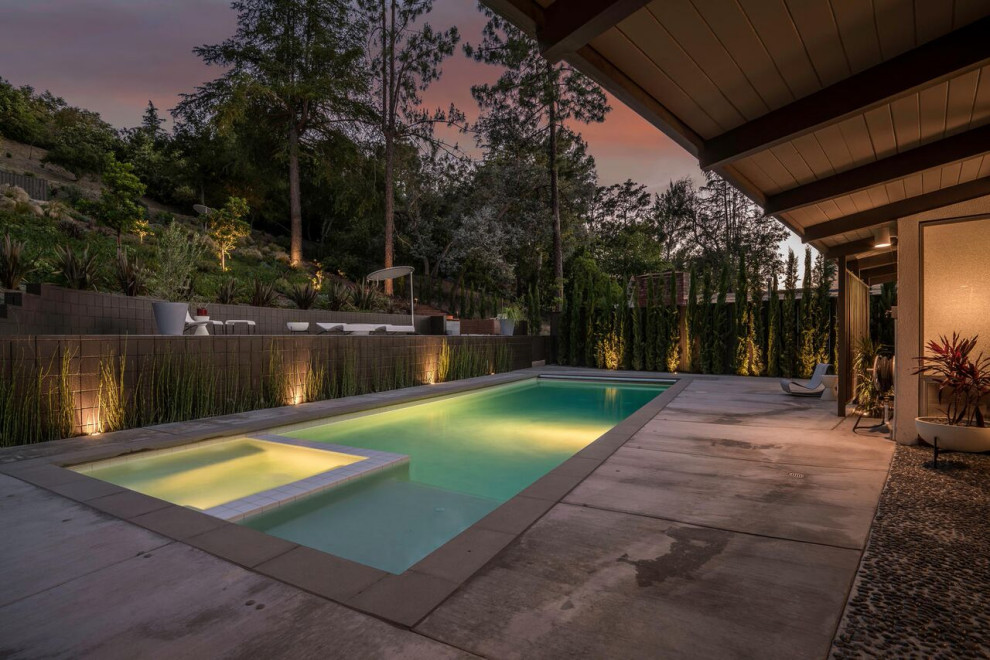 Diseño de piscinas y jacuzzis alargados retro de tamaño medio rectangulares en patio trasero con losas de hormigón