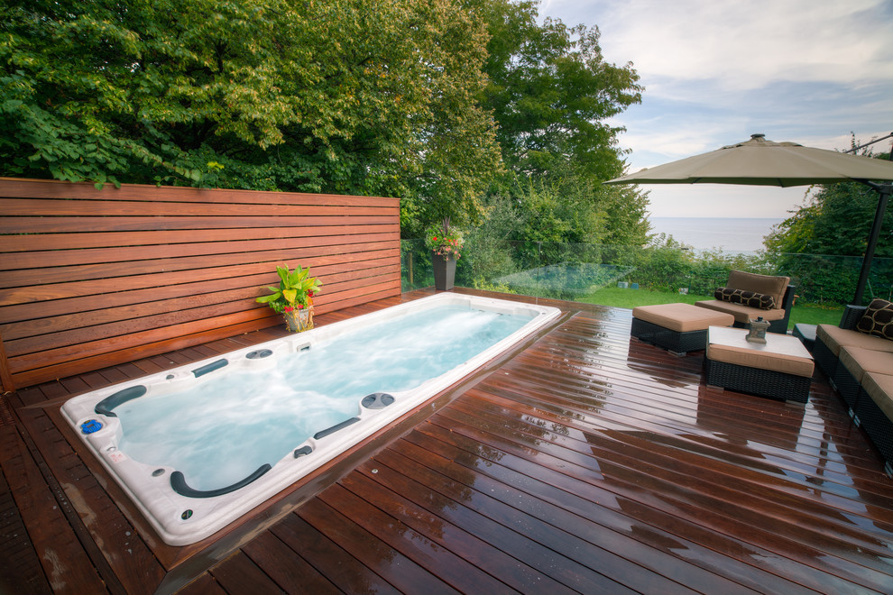 Diseño de piscinas y jacuzzis alargados actuales de tamaño medio rectangulares en patio trasero con entablado