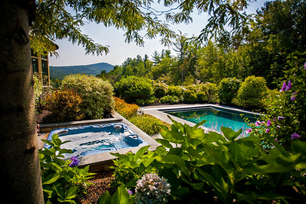 Esempio di una grande piscina monocorsia country rettangolare dietro casa con una vasca idromassaggio e pavimentazioni in pietra naturale