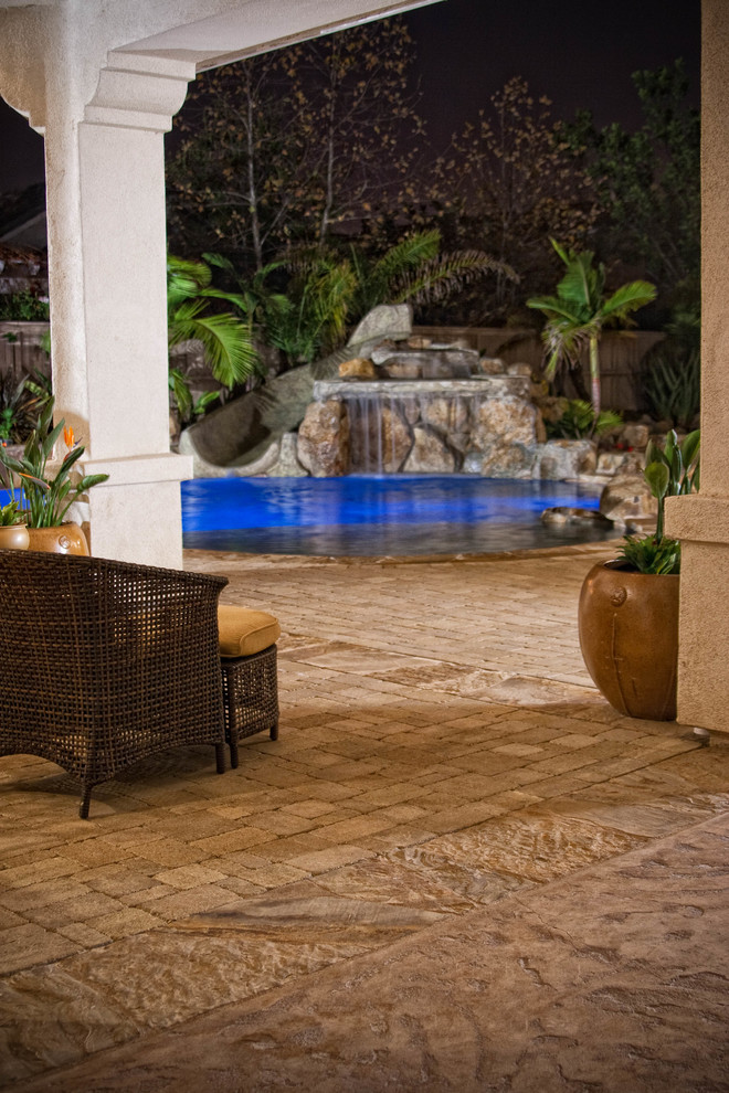 Diseño de piscinas y jacuzzis naturales grandes a medida en patio trasero con adoquines de hormigón
