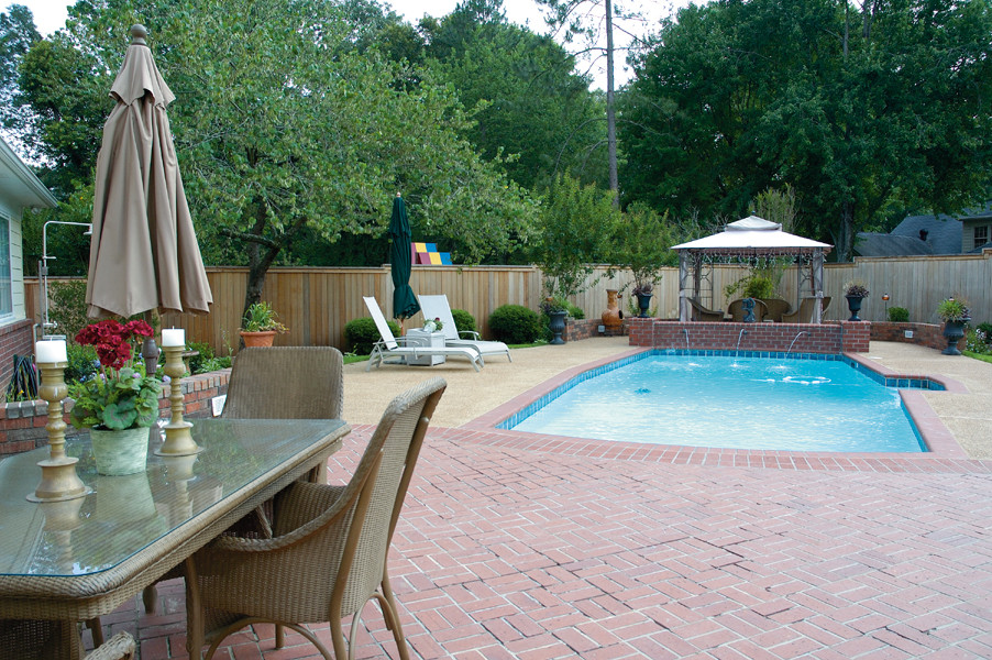 На фото: большой прямоугольный бассейн на заднем дворе с фонтаном и мощением клинкерной брусчаткой с