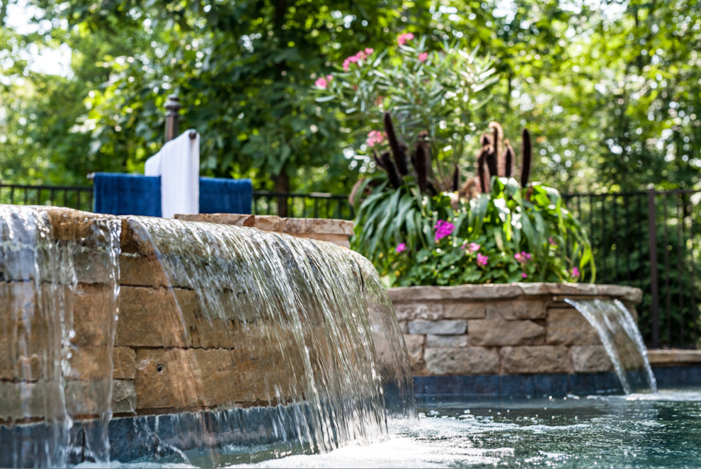 Esempio di una grande piscina naturale classica rotonda dietro casa con fontane e pavimentazioni in pietra naturale