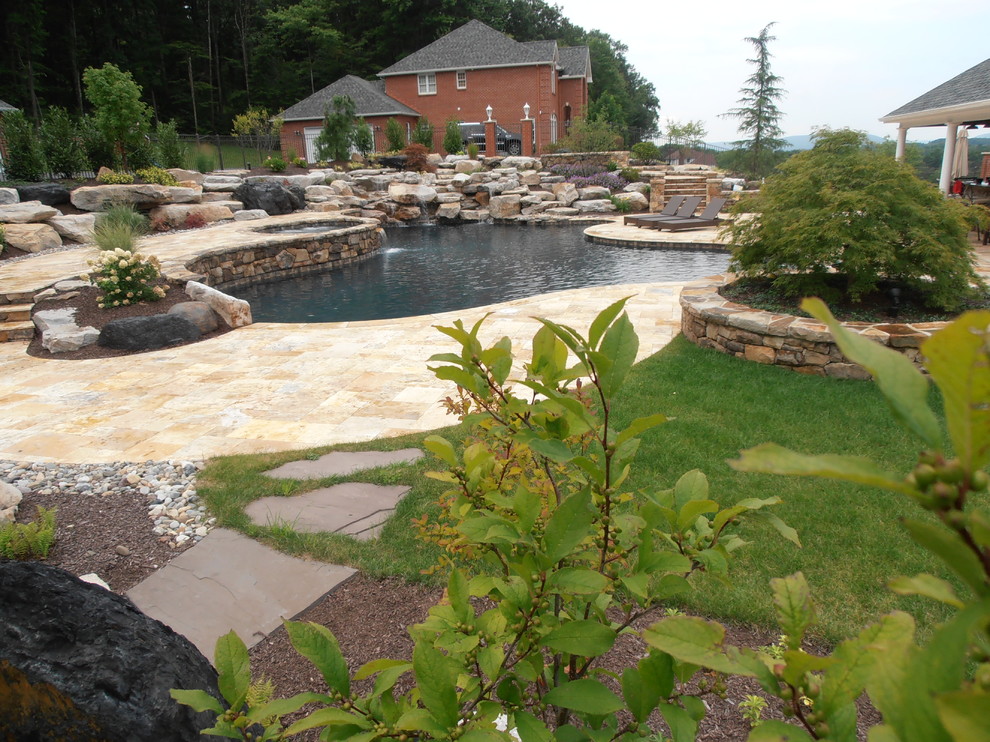 Inspiration pour une grande piscine naturelle et arrière traditionnelle sur mesure avec un point d'eau et des pavés en pierre naturelle.