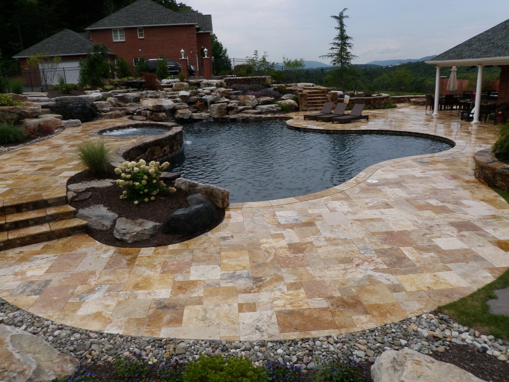 Diseño de piscina con fuente natural clásica grande a medida en patio trasero con adoquines de piedra natural